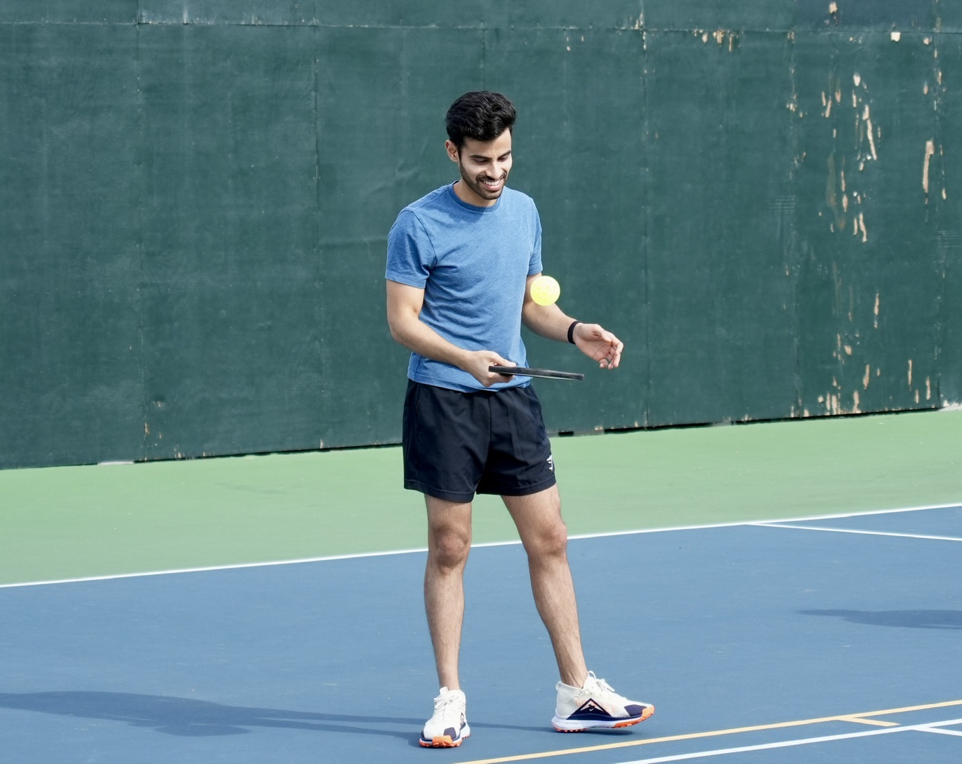 Ribhav on a pickleball court, paddle in hand and the ball in the air